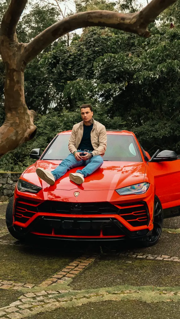 Caio Martins sentado no capô de um carro
